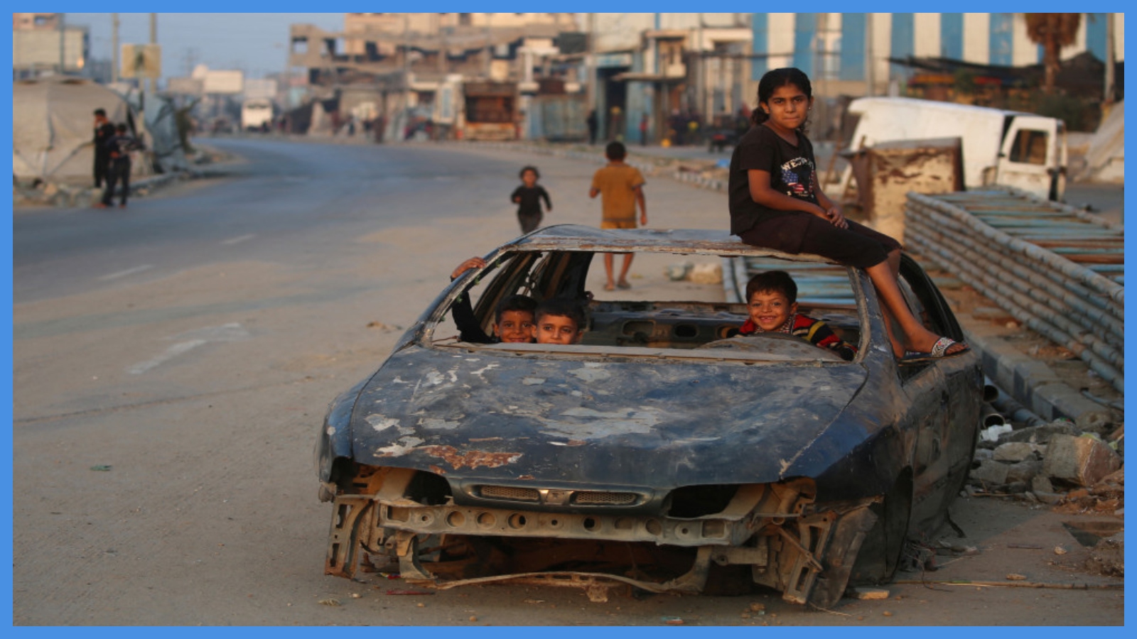 أطفال فلسطينيون يلعبون في سيارة مدمرة في مخيم البريج بقطاع غزة