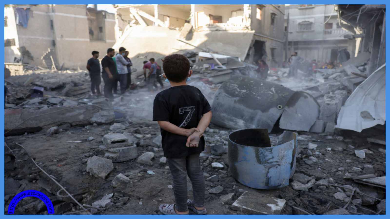 طفل يراقب أشخاصًا يتفقدون موقع غارة إسرائيلية في جباليا وسط قطاع غزة