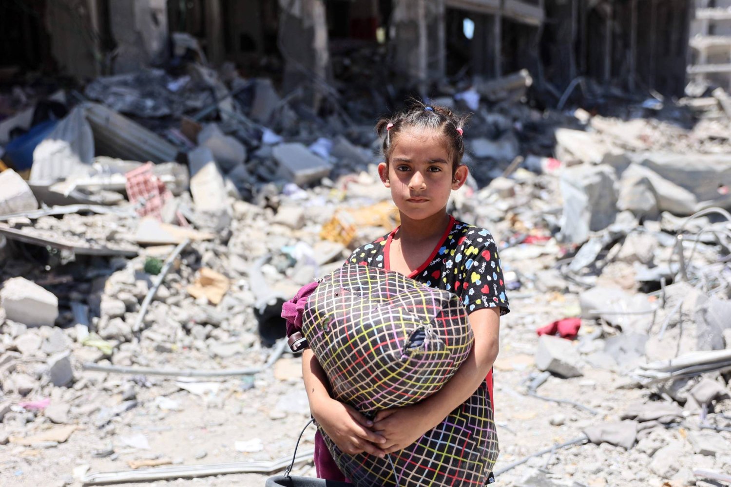 طفلة فلسطينية تحمل بعض الأغراض في مخيم جباليا بشمال قطاع غزة (أ.ف.ب)