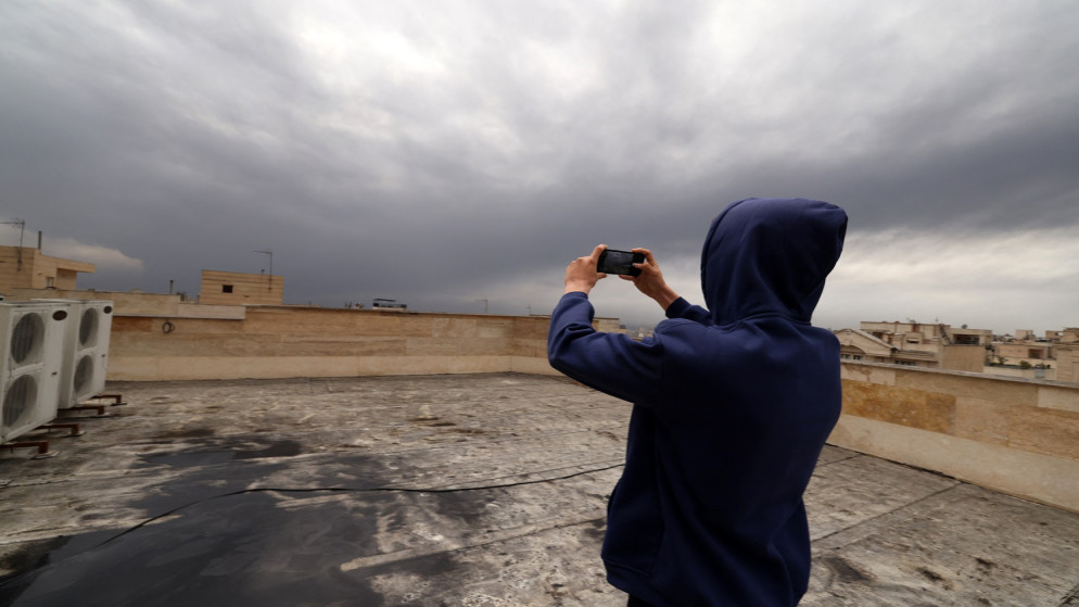 إيراني يلتقط صوراً من على سطح منزله المغطى بالسواد بعد الهجوم على مصفاة النفط في طهران